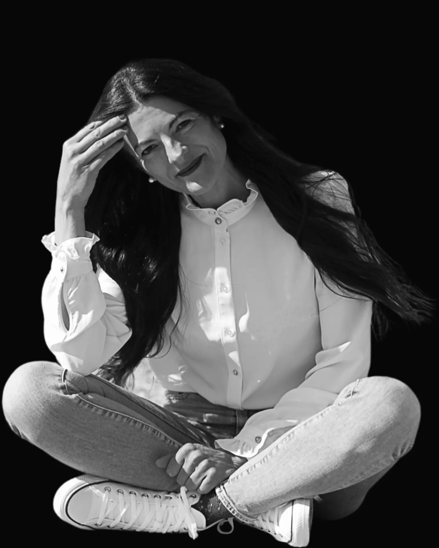Angela Pelli seduta a gambe incrociate, con un sorriso naturale: un ritratto autentico che racconta professionalità e vicinanza.